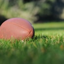 Giants, selective focus photography of brown football on grass at daytime