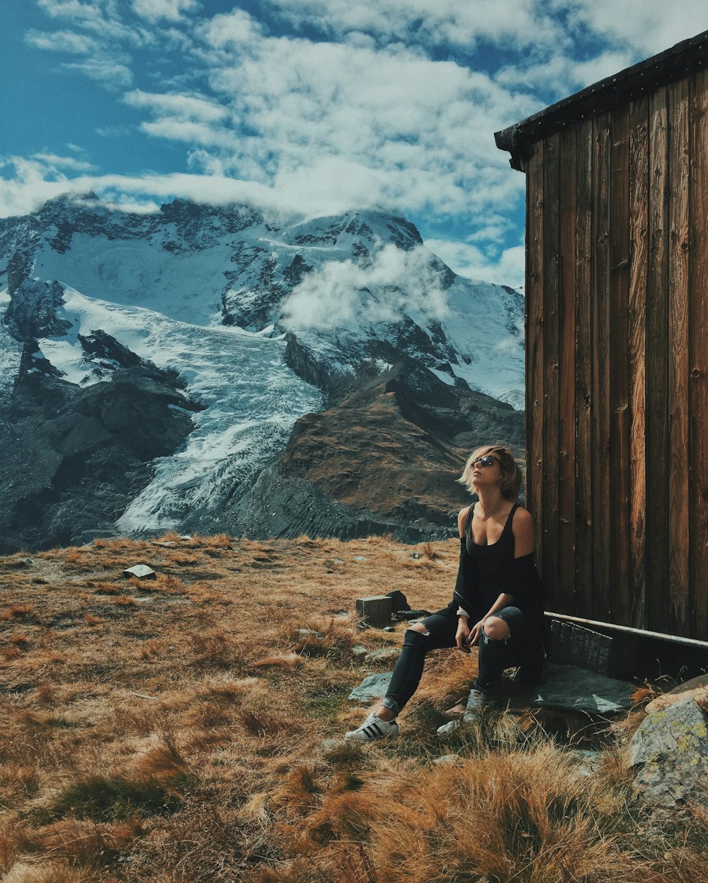 woman sitting beside brown house