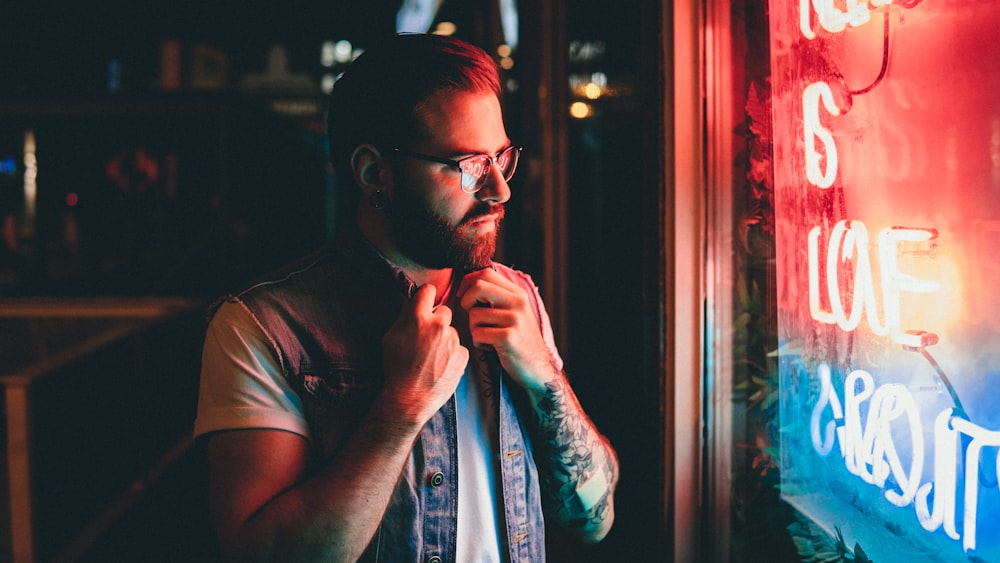 man holding his denim vest looking at widnow