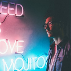 man standing beside white need is love and mojitos neon signage