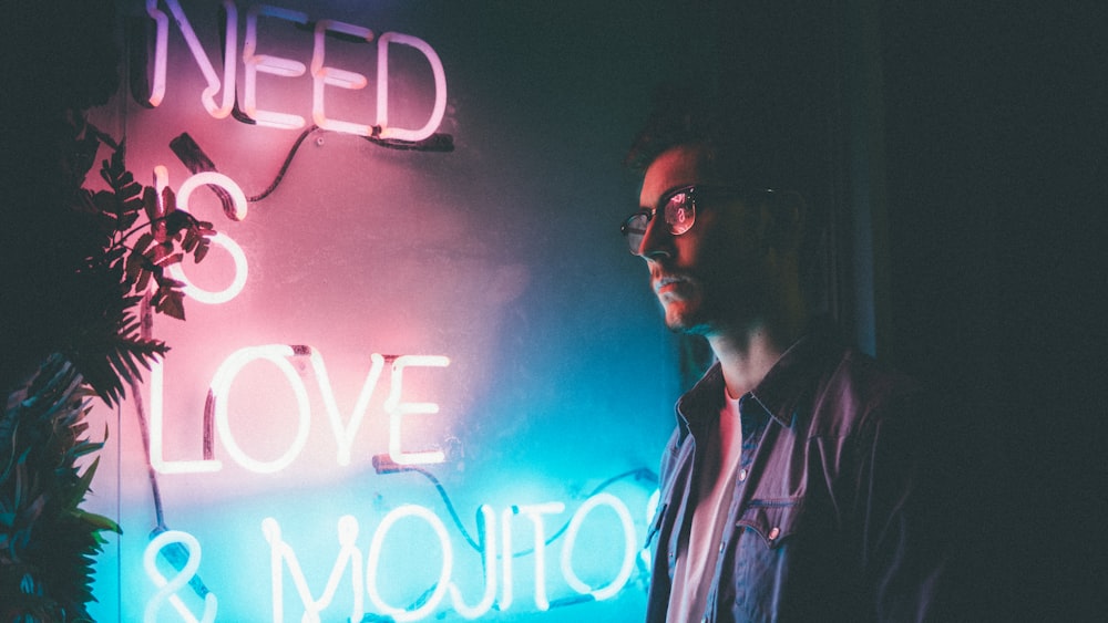 Mann steht neben weißem Bedürfnis ist Liebe und Mojitos Neon-Reklame