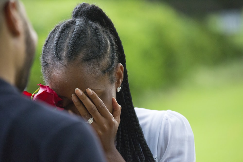 woman wearing white shirt holding rose covering face