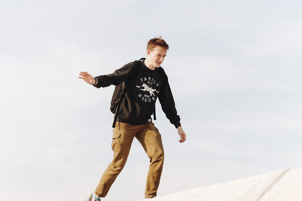 man wearing long-sleeved shirt and khaki pants on top of roof