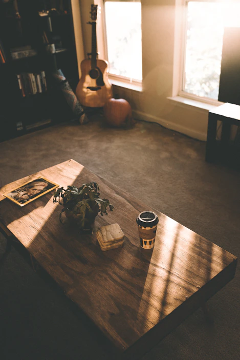 A warm, inviting workspace with books on psychology and faith, a guitar leaning against a chair, and soft natural light.