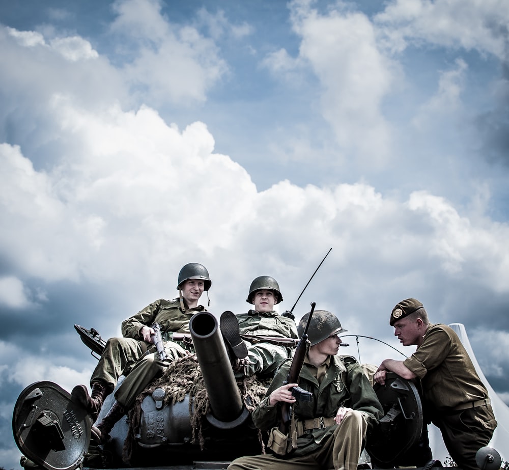 Un grupo de hombres sentados encima de un tanque
