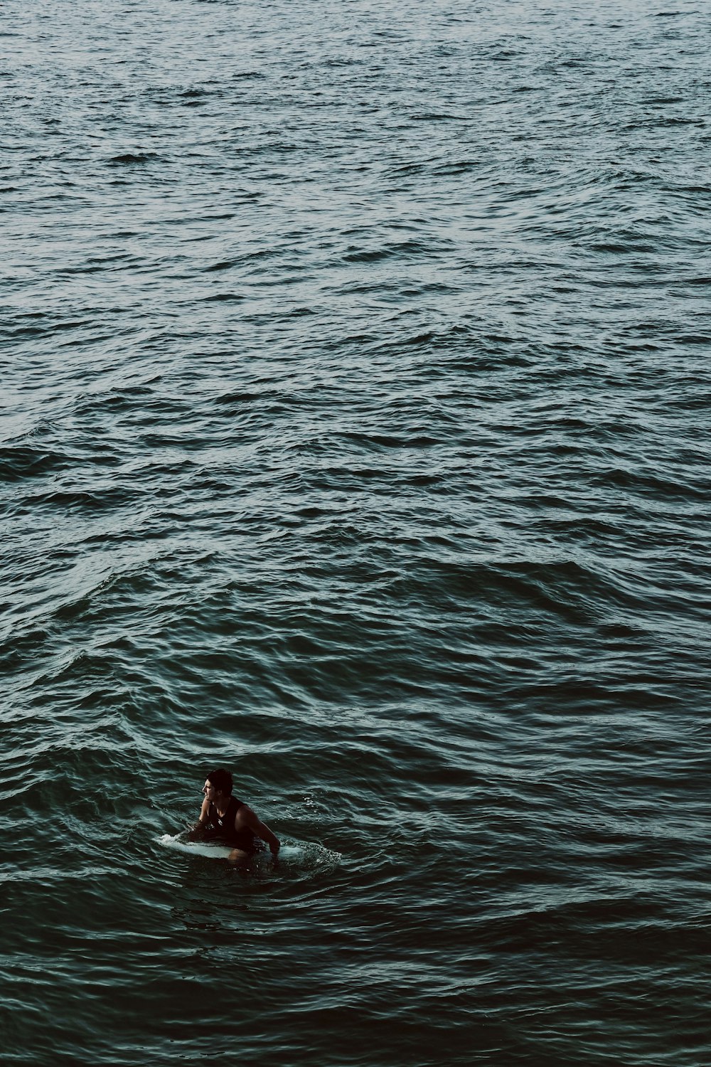 man riding on surfboard on body of water during daytime