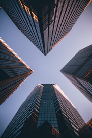 Upward view between modern city skyscrapers representing growth, clarity and premium standards.