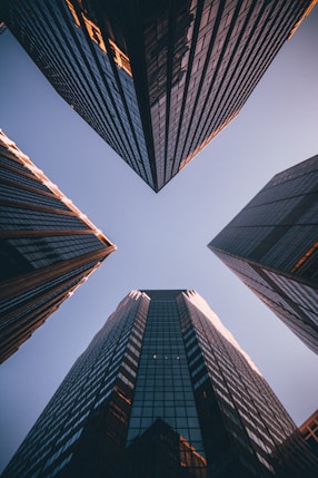 Upward view between modern city skyscrapers representing growth, clarity and premium standards.