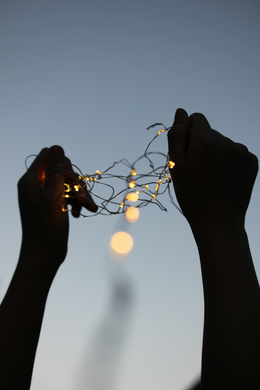 silhouette personne tenant guirlandes lumineuses