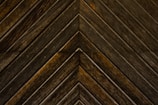 Dark wooden planks arranged in a chevron pattern, displaying distinct grains and a slightly weathered texture.