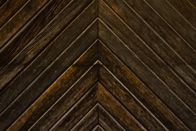 Dark wooden planks arranged in a chevron pattern, displaying distinct grains and a slightly weathered texture.
