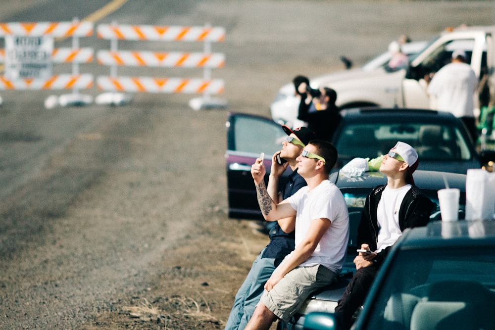 Gruppe von Menschen, die auf dem Auto sitzen, während sie sich eine Flugshow ansehen