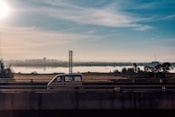 A delivery van equipped with a GPS antenna driving along a busy highway on a clear day.