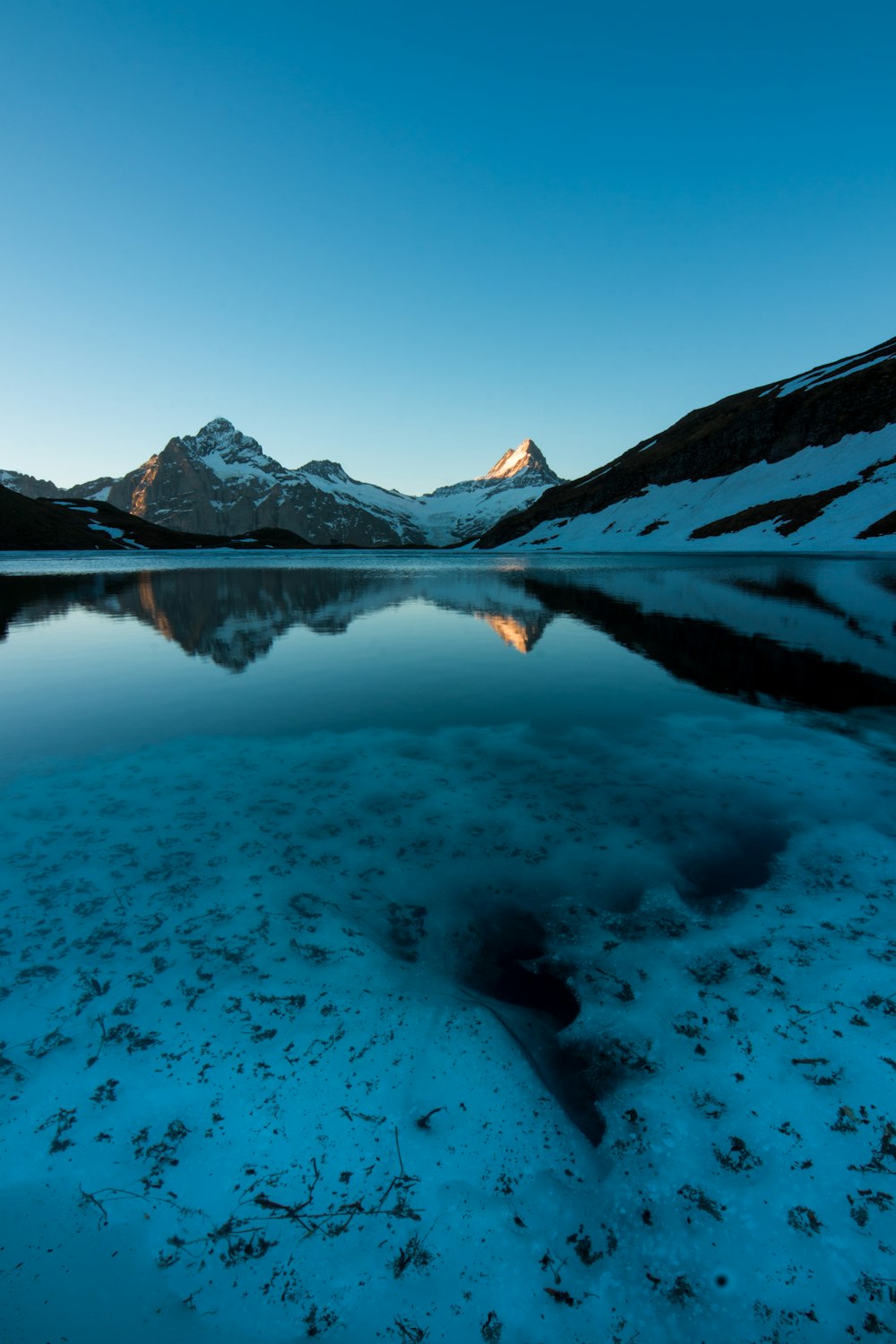 Cuerpo de agua cerca de la montaña bajo el cielo azul durante el día