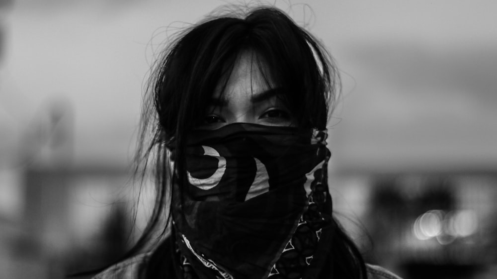 person wearing black mask in grayscale photography