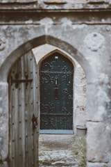 opened gray wooden door with closed green wooden door at the distance