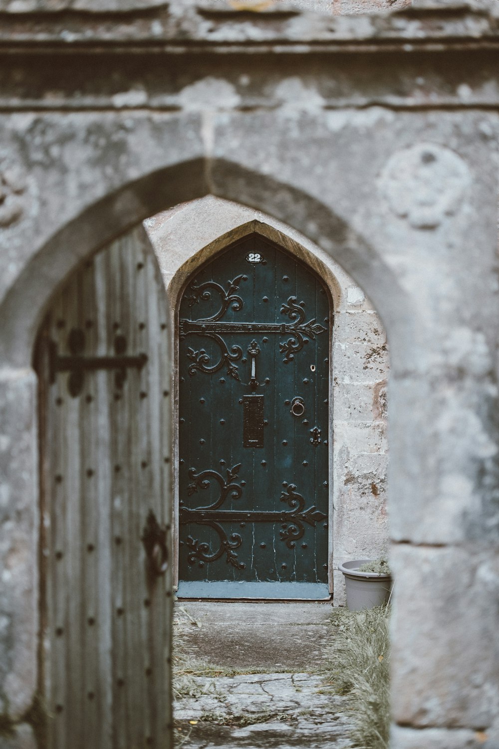 opened gray wooden door with closed green wooden door at the distance