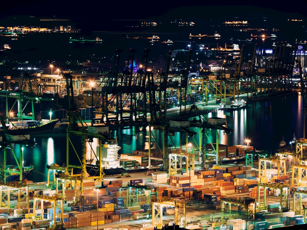 scaffoldings and metal racks near body of water and lighted building during nighttime