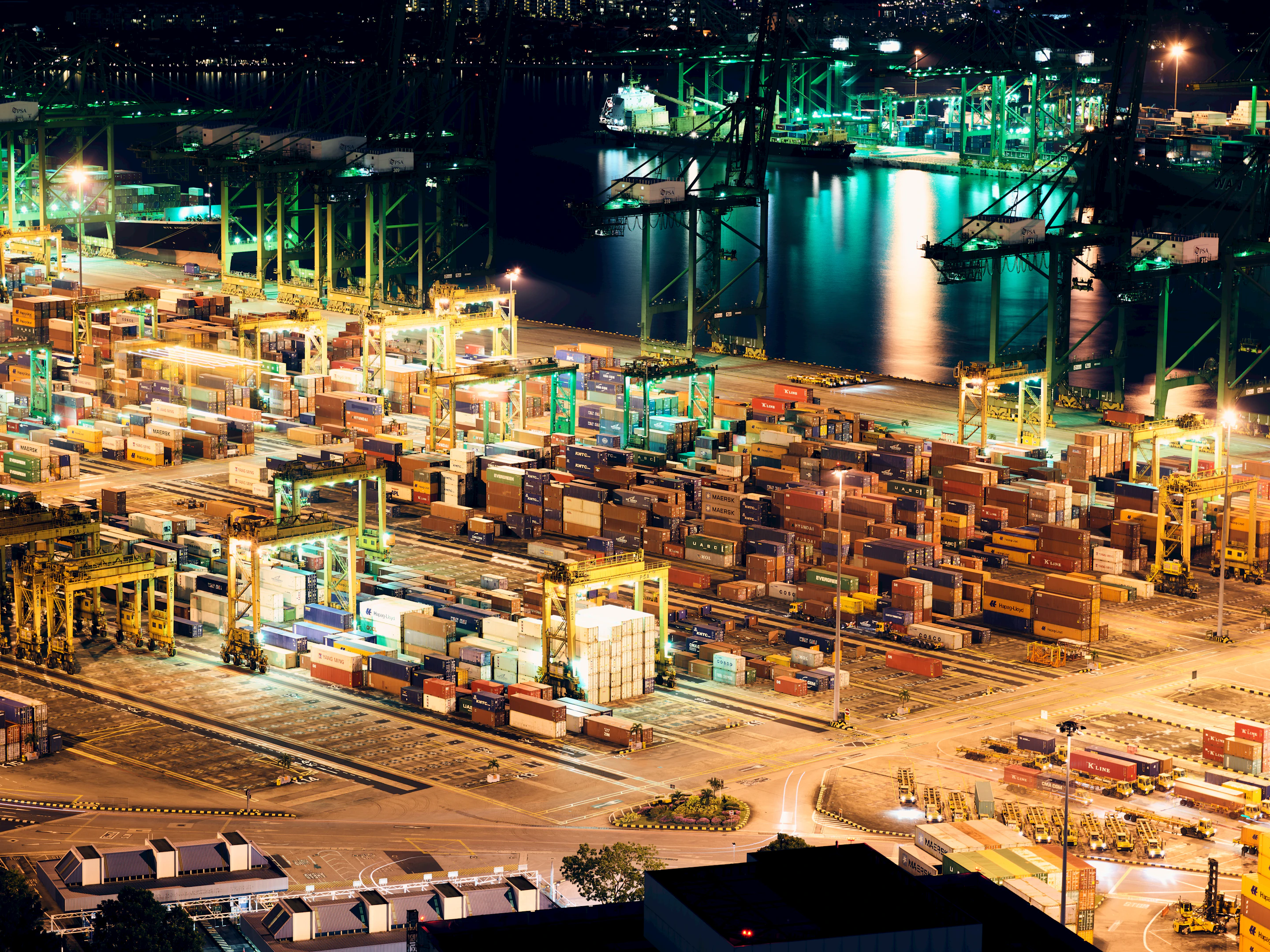 Vista aérea nocturna de terminal portuario intermodal con patio de contenedores
