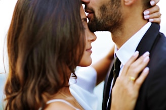man kissing woman on her forehead