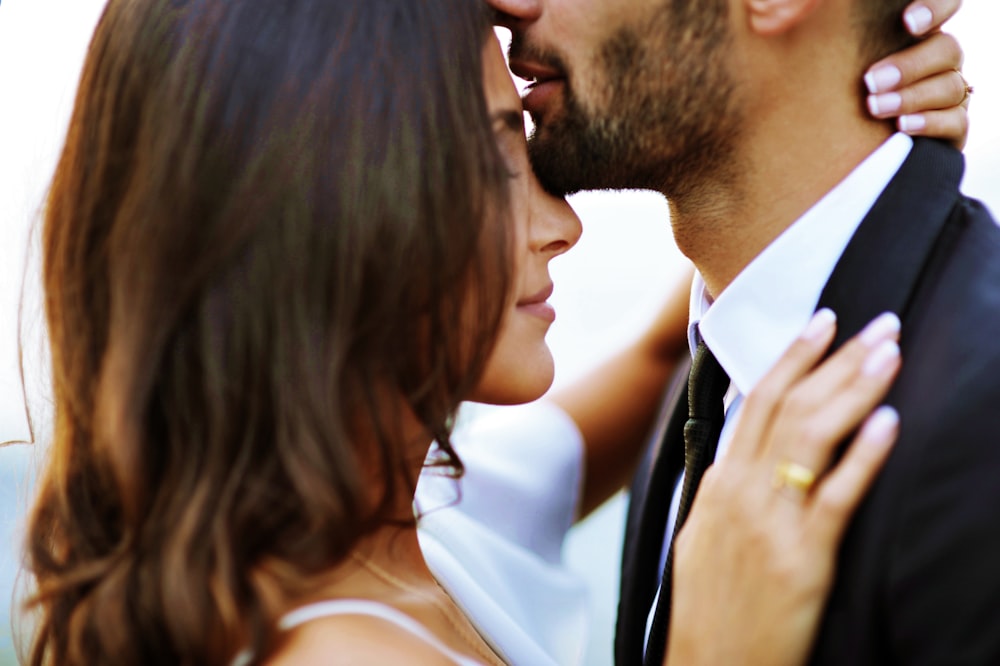 man kissing woman on her forehead