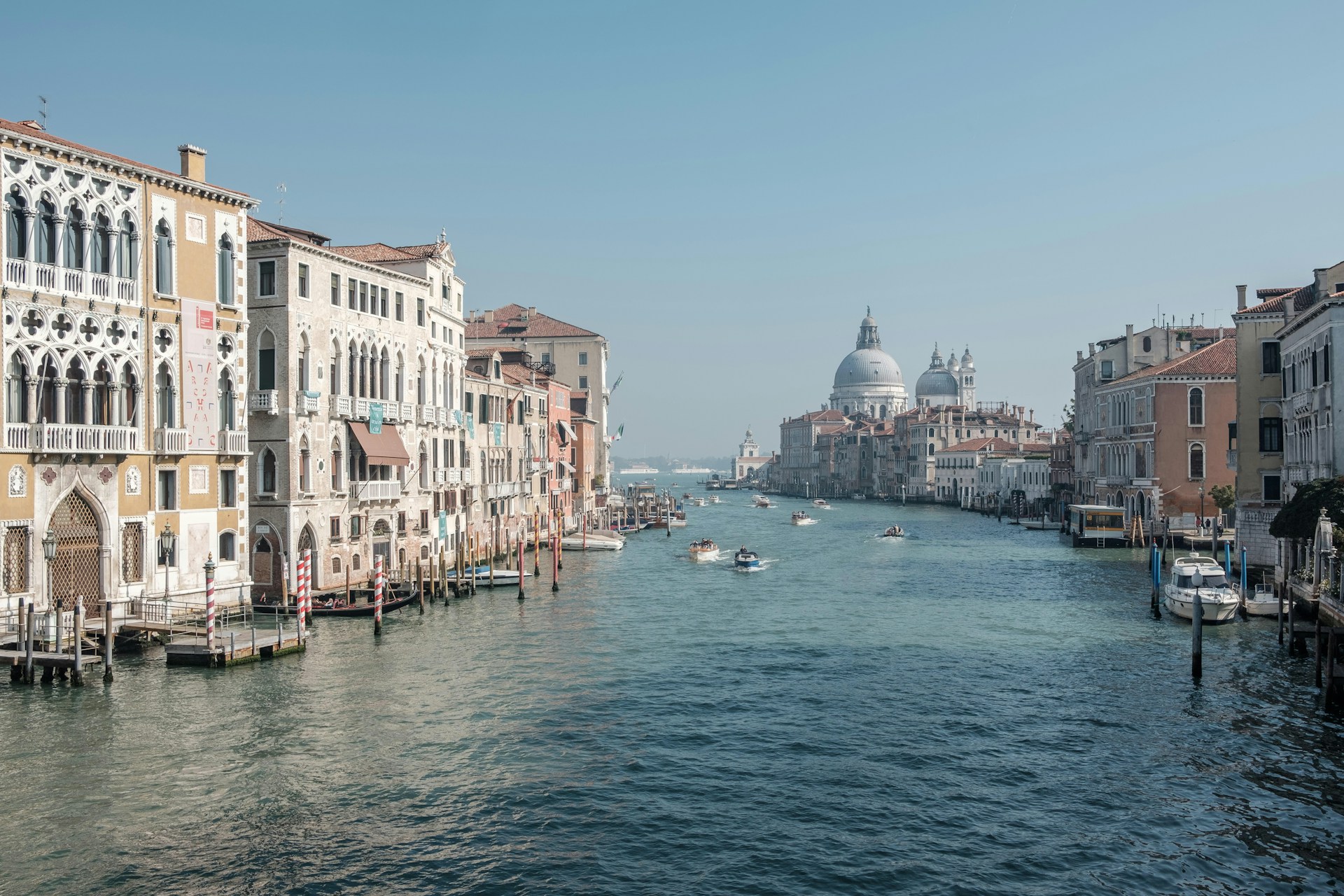 boats running on sea between buildings