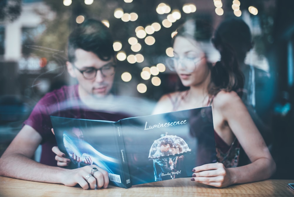 man sitting beside woman while reading