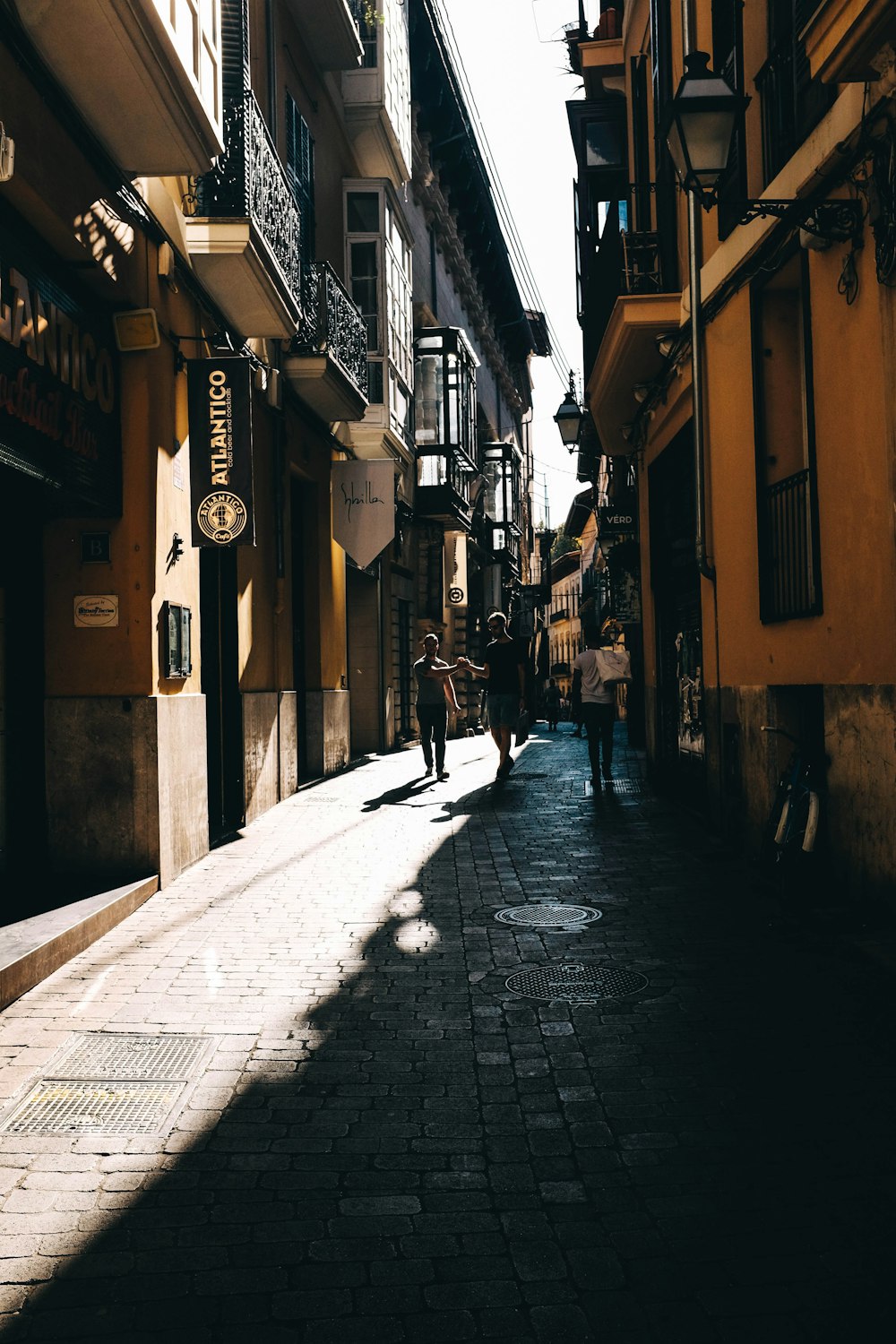 three person walking in between two buildings