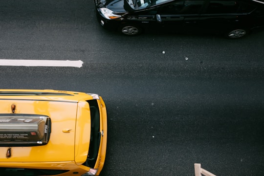 yellow car beside a black car on a black road