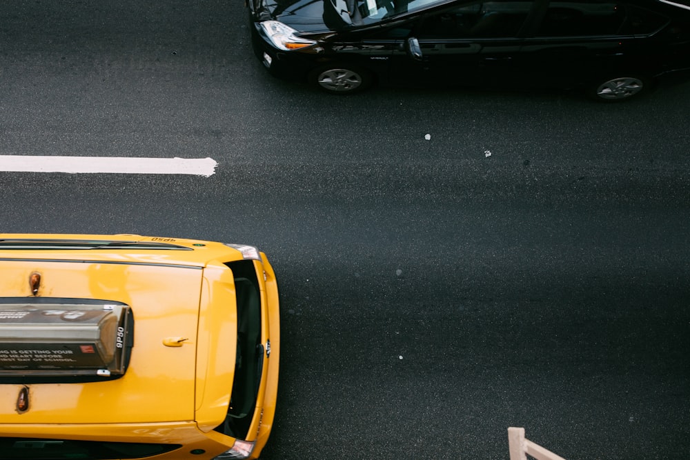 yellow car beside a black car on a black road