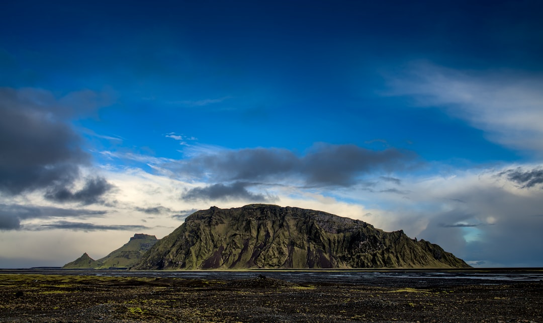 brown mountain near body of water at daytime