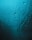 Water droplets and streaks move down a smooth surface, possibly glass, with a blue-green tint. The light gives the surface a shimmering appearance, creating a sense of wetness and fluidity.