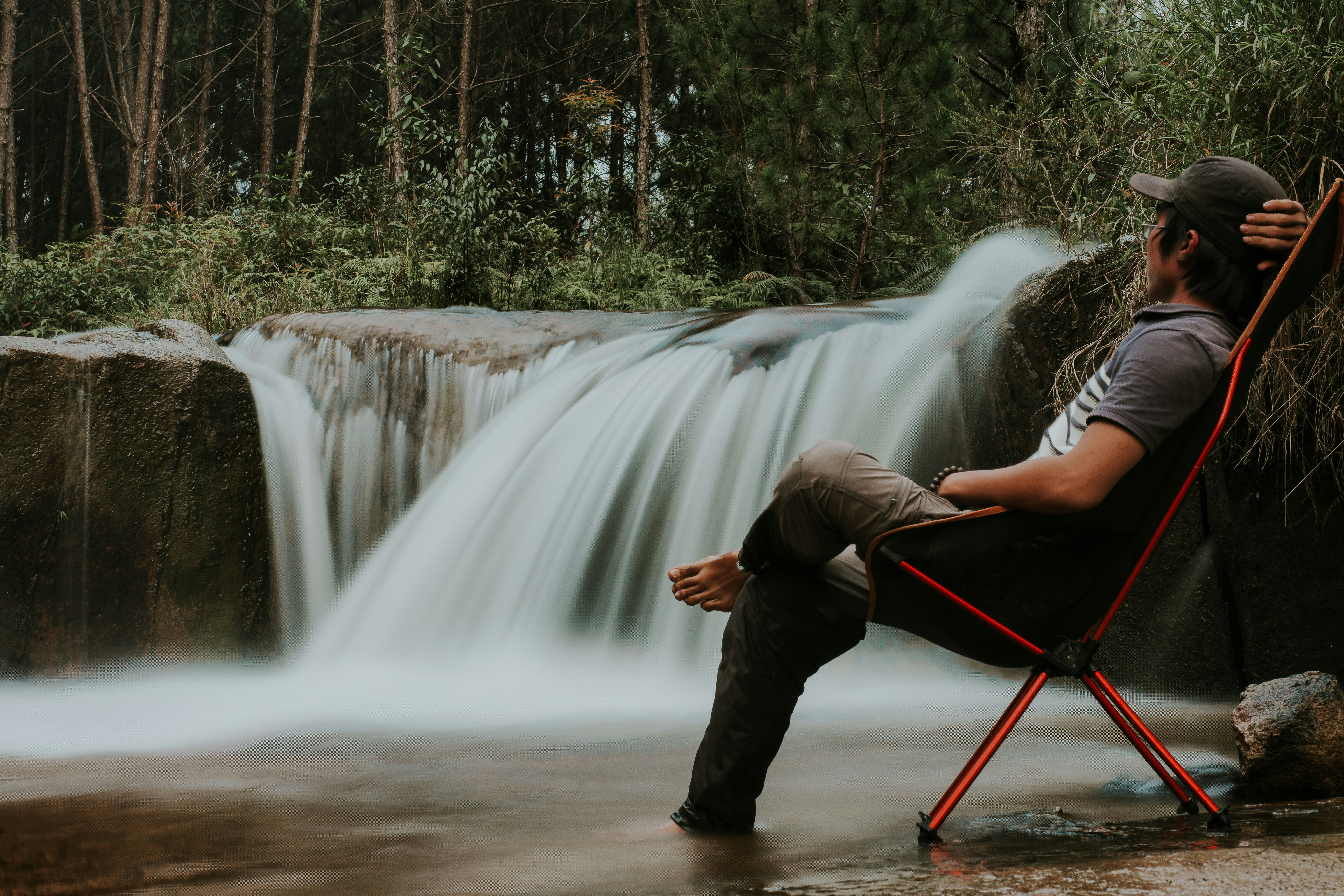 折り畳み椅子に座って昼間、滝を眺める男