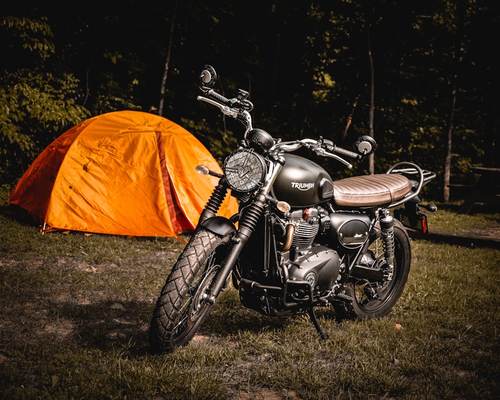 オレンジ色のキャンプテントの横に駐車された茶色の裸のバイク