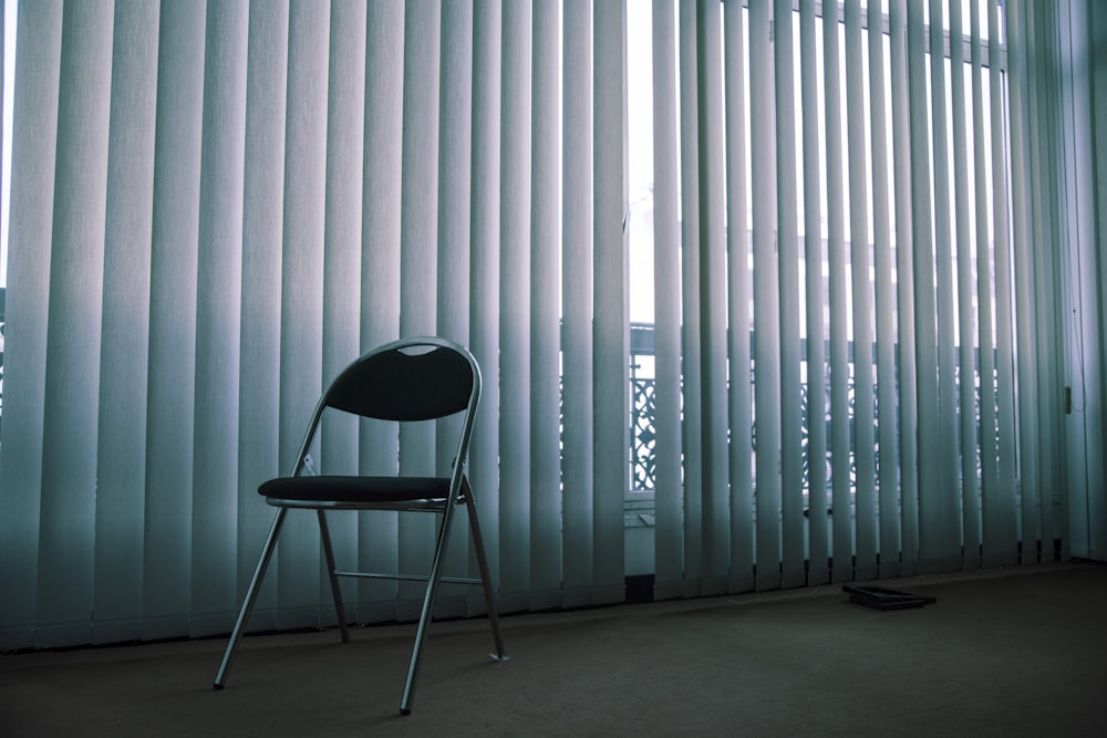 gray folding chair near white window blinds