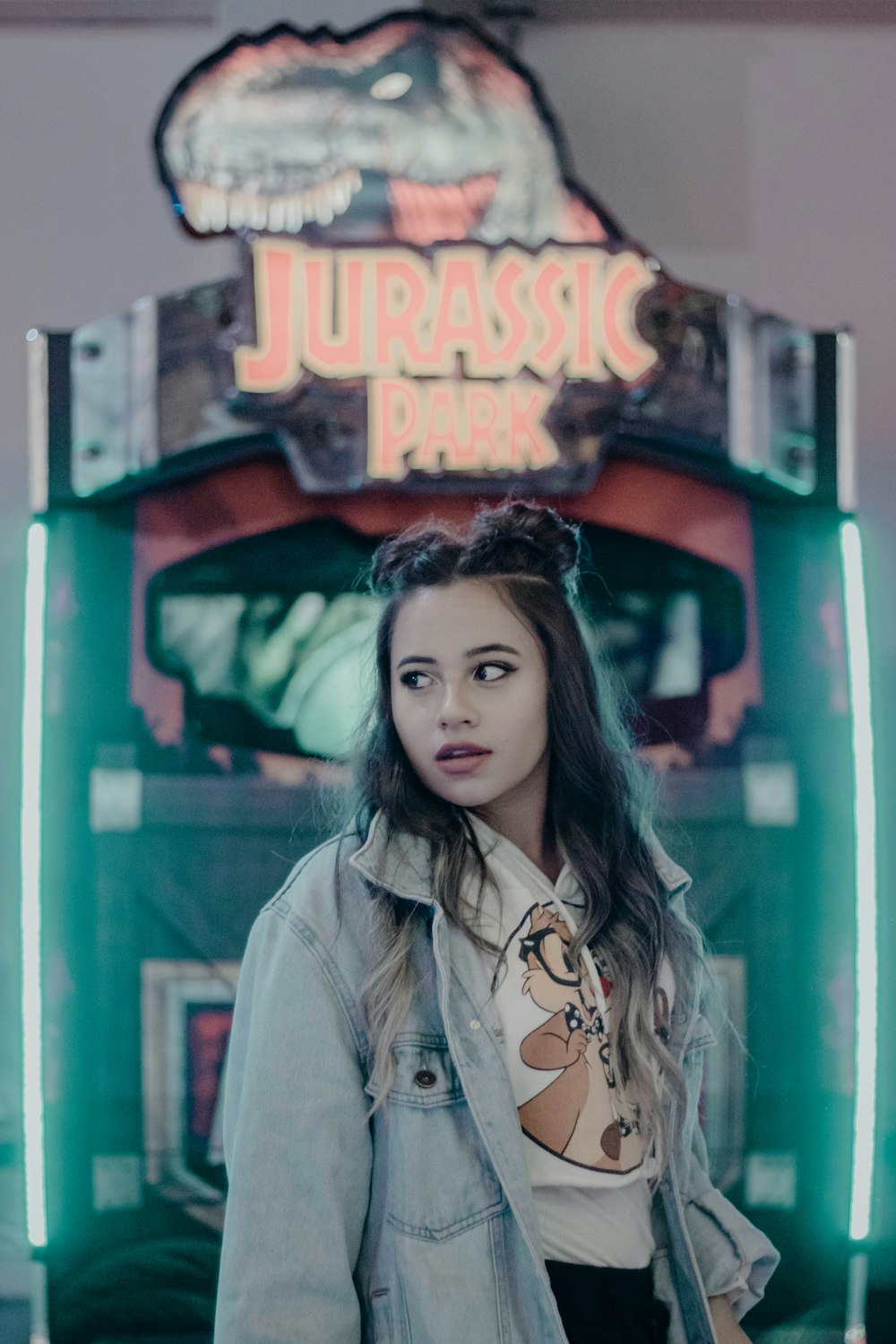woman standing in front of Jurassic Park arcade game machine