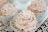 Delicate cupcakes with creamy frosting and small edible flowers on top.