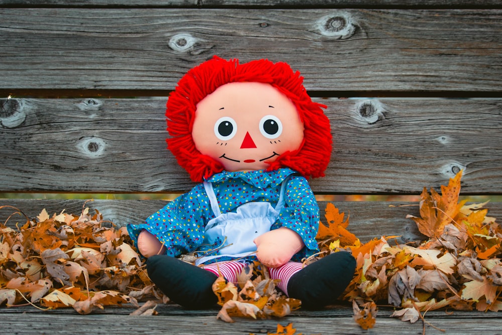 doll on gray wooden bench with maple leaves