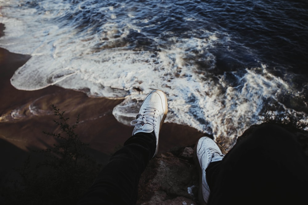 person sitting on rock near seashore