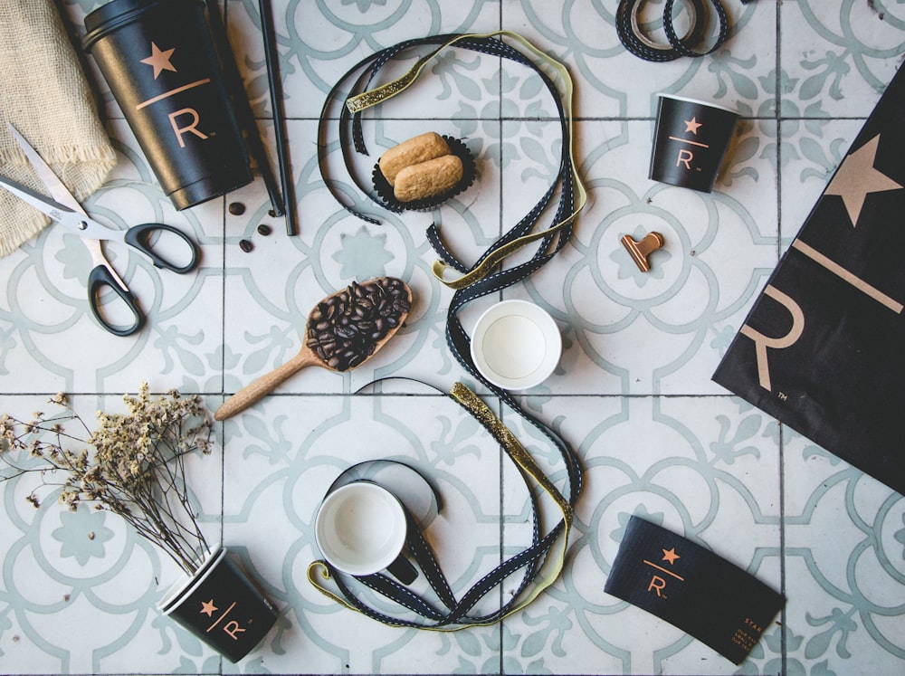 brown and black straps near coffee beans and cups on gray tiles