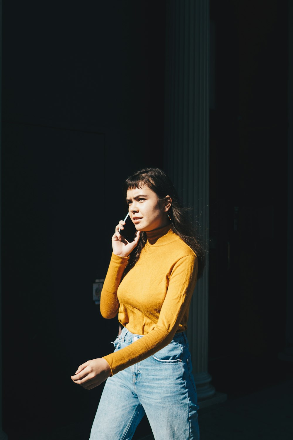 Mujer que camina con el teléfono en la oreja derecha durante el día