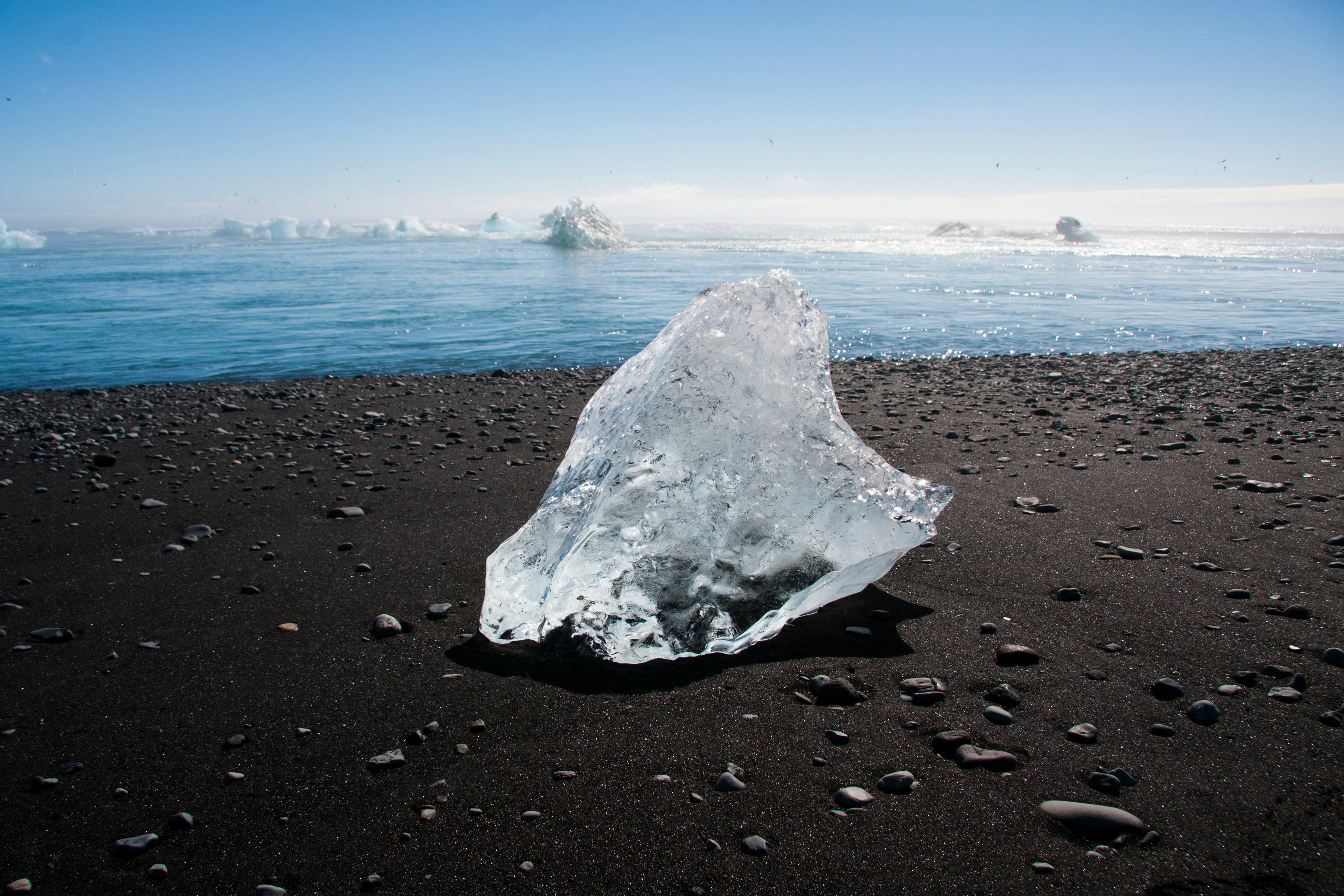 ice melting on brown sand during daytime