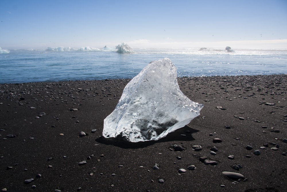 ice melting on brown sand during daytime