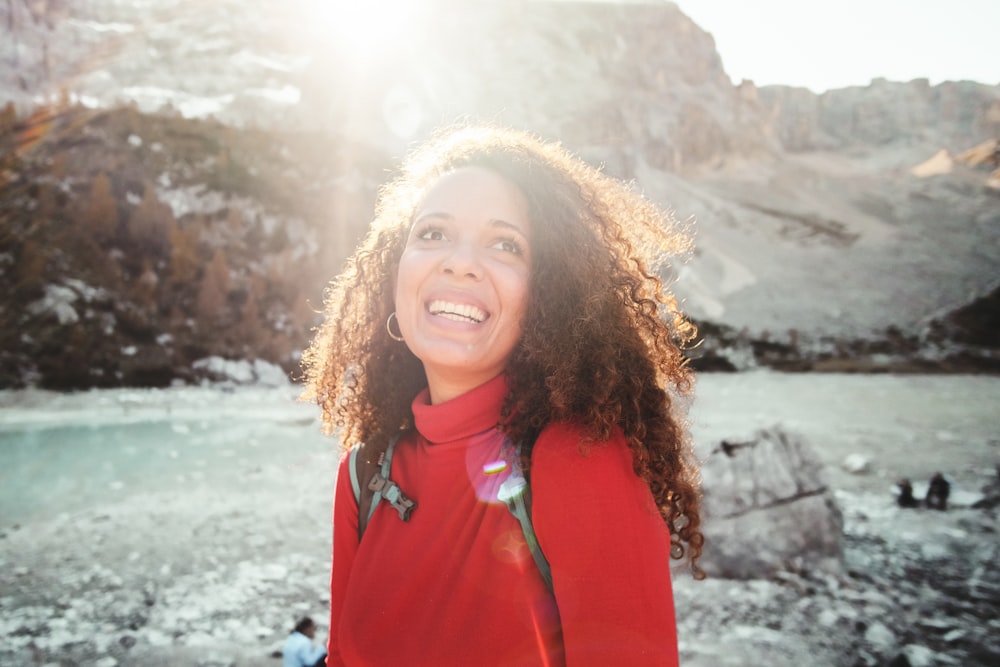 woman wearing red turtle neck shirt near mountain