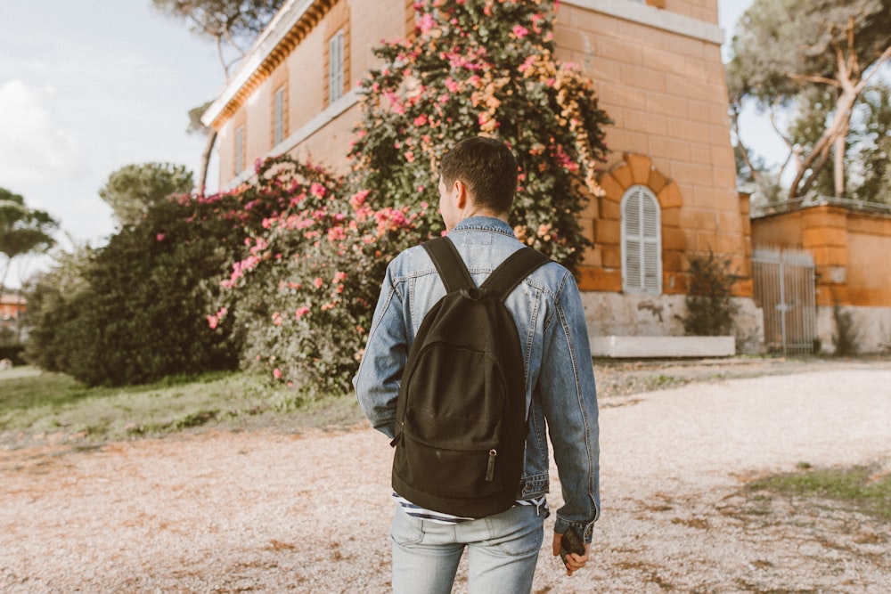 man with backpack standing in front of a house