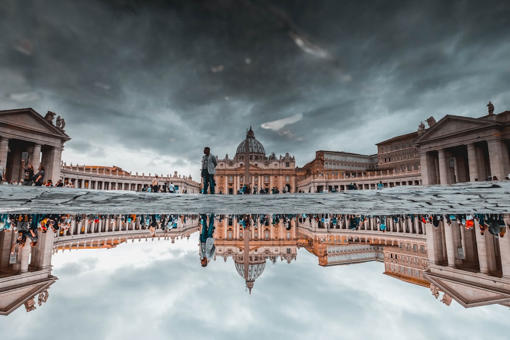 reflection of people standing near building under gray sky