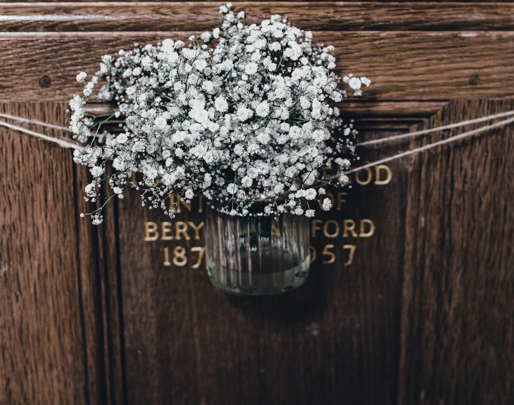 flores blancas en jarrón de vidrio transparente que cuelga en la puerta