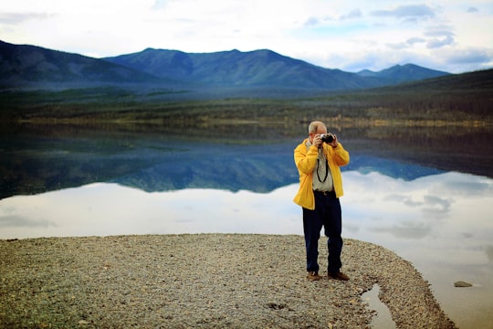 man in yellow jacket taking pictures during daytime in Going-To-The-Sun Road United States