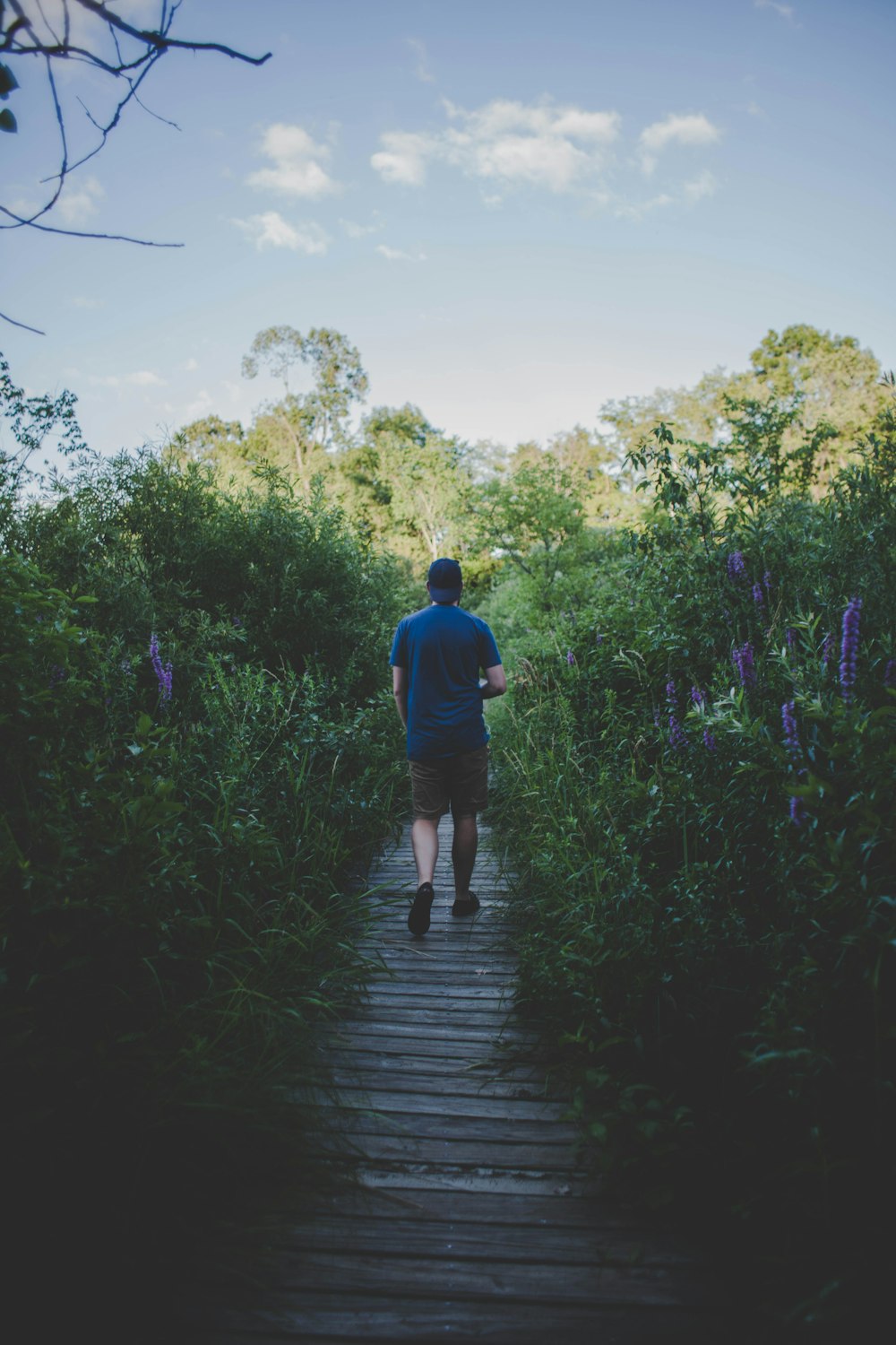 man in blue crew-neck shirt while walking on brown dock