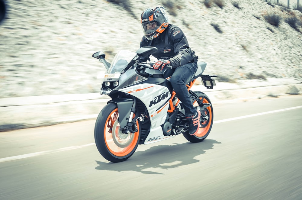 man riding white and orange KTM sports bike